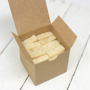 May include: A brown cardboard box with the lid open, revealing a stack of rectangular bars of white soap.
