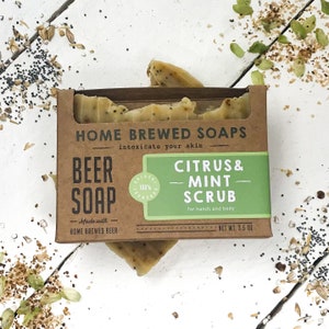 May include: A brown cardboard box with a green and white label that reads "Home Brewed Soaps" and "Citrus & Mint Scrub". The soap is made with 100% home brewed beer and is 3.5 oz.