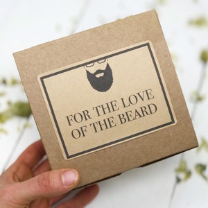 May include: A brown cardboard box with a label that says "FOR THE LOVE OF THE BEARD". The label has a black and white illustration of a man with a beard and glasses.