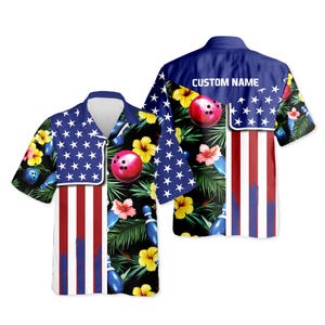 May include: Short-sleeved bowling shirt with a patriotic design. The shirt features a blue collar and a pattern of red, white, and blue stripes, stars, bowling pins, and bowling balls. The background is black with tropical flowers.