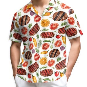 May include: White button-up shirt with a watercolor pattern of grilled steaks, tomatoes, orange slices, peppers, and herbs. The short-sleeved shirt has a camp collar and is worn with white pants. The shirt's design is a food-themed pattern.