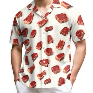 May include: Short-sleeved button-down shirt with a white background and a repeating pattern of realistic-looking raw steak cuts in shades of red and brown. The shirt has a classic collar and is worn with white pants.