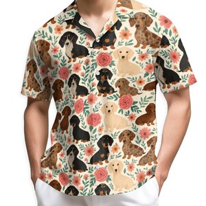 May include: Short-sleeved button-down shirt featuring a repeating pattern of dachshund dogs in various colors, interspersed with pink roses and green foliage on a cream background. The shirt has a classic collar and a relaxed fit.