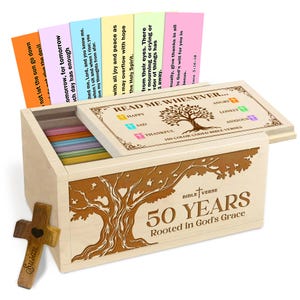 May include: A wooden box set with a tree design and the text "50 YEARS Rooted in God's Grace." The box contains color-coded Bible verses and a wooden cross with the name "Susan." The box lid reads "Read Me Whenever..."