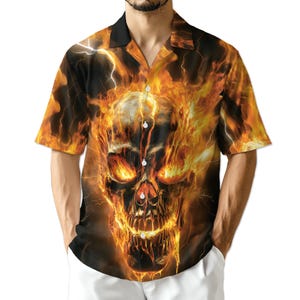 May include: Short-sleeved button-up shirt featuring a fiery skull design. The shirt has a black collar and a vibrant orange, yellow, and black color scheme. The skull graphic is detailed with flames and lightning.