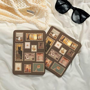 Puede incluir: Dos estuches rectangulares marrones con diseños de sellos con temática de Halloween. Los sellos presentan imágenes de fantasmas, gatos negros, calabazas y escenas otoñales. Gafas de sol negras y una bolsa de red color crema también están en la imagen.