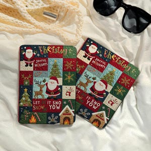 Puede incluir: Dos posavasos cuadrados acolchados con temática navideña. Cada posavasos presenta un diseño de patchwork con Papá Noel, renos, árboles de Navidad y copos de nieve. El texto incluye "Christmas", "Joyful Holidays" y "Let It Snow".