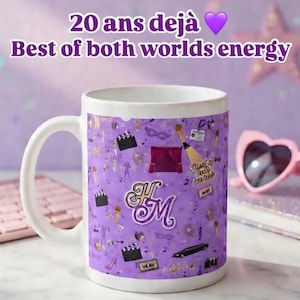 May include: White ceramic mug with a purple pattern featuring film-related icons and the initials "H M". The mug has the text "20 ans d&eacute;j&agrave;" and "Best of both worlds energy". Pink heart-shaped sunglasses and a keyboard are in the background.