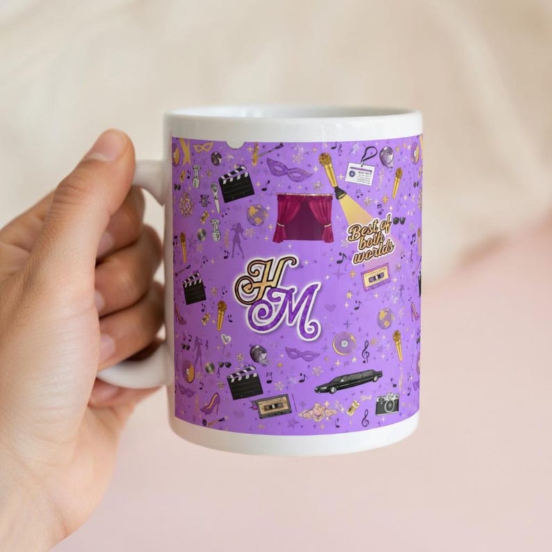 May include: White ceramic mug with a purple background featuring various entertainment-themed icons. The mug has the text "Best of both worlds" and the initials "HM" in a decorative font. Other icons include a film clapper, a stage, and a camera.