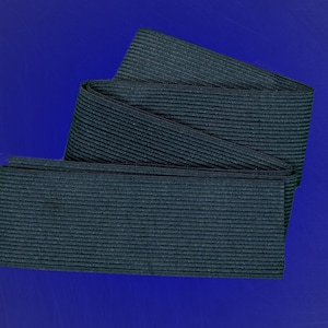 May include: Dark navy blue elastic band, folded and displayed against a deep blue background. The band has a ribbed texture, and is likely used for sewing or crafting projects. The image is well-lit, highlighting the texture.