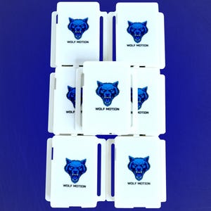 May include: White rectangular cards with a blue wolf head logo and the text "WOLF MOTION" are stacked on a blue background. The wolf head is a detailed illustration with sharp teeth. The cards are arranged in a grid.
