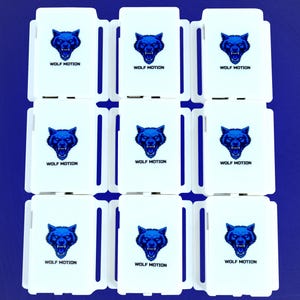 May include: Nine white rectangular objects with a blue wolf head logo and the text "WOLF MOTION" arranged in a grid on a blue background. The wolf logo is a detailed illustration.