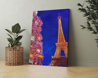 Puede incluir: Impresión en lienzo de la Torre Eiffel iluminada de noche, con un cielo azul profundo de fondo. A la izquierda, un edificio cubierto de flores rosas. Una escena parisina.