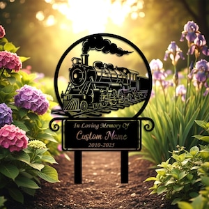May include: Black metal memorial garden stake featuring a detailed train design within a circular frame. The stake includes a rectangular plaque with the text "In Loving Memory Of Custom Name 2010-2025". The stake is placed in a garden setting.