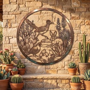 Peut inclure: Une décoration murale circulaire en métal représentant une scène désertique avec un grand géocoucou, un lièvre et une caille avec ses poussins parmi des cactus et des agaves. L'œuvre a une finition bronze sur un mur en pierre texturé.