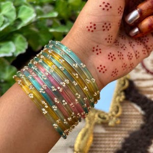 以下が含まれることがあります： 白いセラミックマグカップ、黒いハンドル、手書き風の「But First, Coffee」の文字。マグカップは白い表面に置かれています。マグカップの高さは約10cmです。