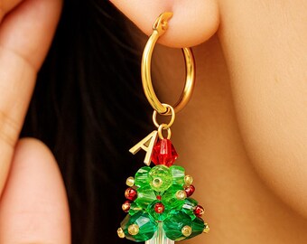May include: Gold hoop earring with a Christmas tree charm. The charm is made of green and red beads, with a small gold letter "A" at the top. The earring is worn on a person's ear.
