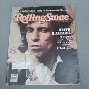 Puede incluir: Una revista Rolling Stone vintage con Keith Richards en la portada. El título de la revista, "Rolling Stone", se muestra en una fuente roja y blanca. La portada también incluye el texto "KEITH RICHARDS No Regrets The Rolling Stone Interview By Kurt Loder."