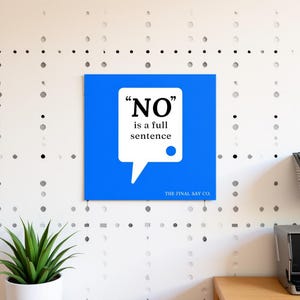 May include: A square, blue wall art piece with the text "NO" in large, bold letters inside a white speech bubble. The text "is a full sentence" is below the word "NO". The bottom right corner of the art piece has the text "THE FINAL SAY CO."