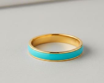 May include: A gold ring featuring a vibrant turquoise enamel band. The ring's design is simple and elegant, with a smooth, polished finish. The turquoise band is central, creating a striking contrast against the gold. The ring is approximately 0.5 cm wide.