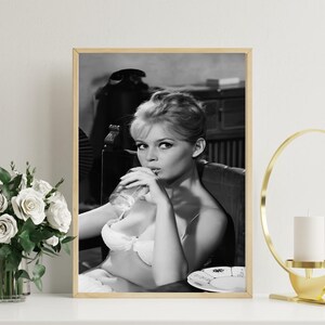 Puede incluir: Impresi&oacute;n enmarcada en blanco y negro que muestra a una mujer bebiendo de un vaso. La mujer lleva un sujetador blanco y est&aacute; sentada en una silla. Un plato con un dise&ntilde;o est&aacute; sobre una mesa. La impresi&oacute;n est&aacute; en un marco de madera.