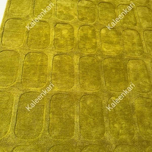 May include: A chartreuse area rug featuring a repeating pattern of raised, rounded rectangular shapes across the entire surface. The word Kaleenkari is printed in white text multiple times across the rug in a diagonal orientation.