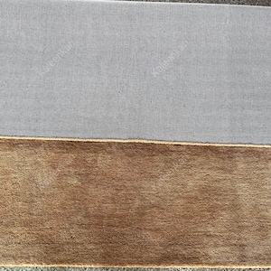 Puede incluir: Vista de cerca de dos alfombras rectangulares. La alfombra superior es de color gris liso, y la alfombra inferior es de color marr&oacute;n liso. El texto "Kaleenkan" est&aacute; impreso en ambas alfombras.