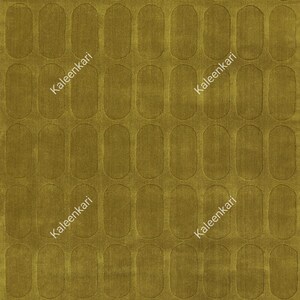 May include: A mustard yellow rug featuring a repeating pattern of vertical pill-shaped indentations across the entire surface. The text Kaleenkari is printed diagonally in white across the rug in two separate locations on the fabric.