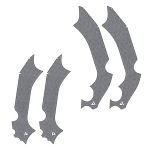 May include: Six gray, textured, curved adhesive pads with pointed edges and a small triangle logo. The pads are arranged in two groups of three, designed for a specific application. The overall shape is elongated and asymmetrical.