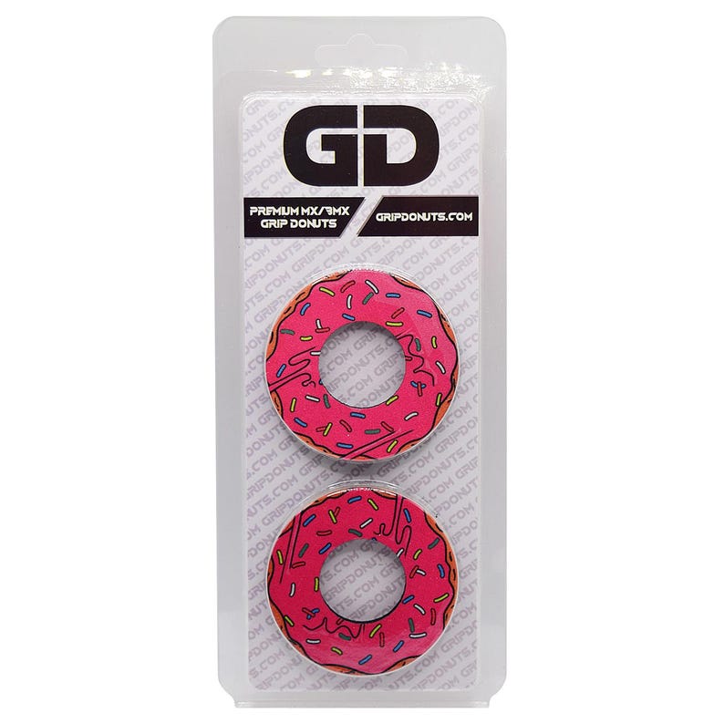May include: Two pink donut-shaped grip donuts with sprinkles and brown icing, packaged in a clear plastic blister pack. The package has the text "GD" and "GRIPDONUTS.COM".