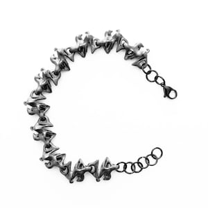 Peut inclure: Un bracelet à chaîne de couleur argent foncé composé d'une série de maillons géométriques angulaires et texturés interconnectés. Le bracelet comprend une fine chaînette d'extension en métal noir avec des maillons circulaires et un fermoir mousqueton.