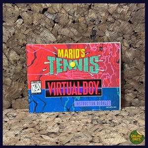 May include: A retro video game cartridge for "Mario's Tennis" on the Virtual Boy. The box features a red and blue design with the game title in large, green letters. The instruction booklet is visible.
