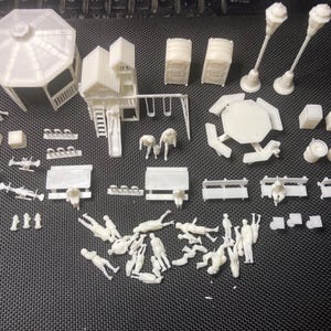 Puede incluir: Una colección de figuras de plástico blanco en miniatura sin pintar y estructuras de parque, que incluye un cenador, un juego de parque infantil con columpios, bancos, mesas de picnic, farolas, baños portátiles y varias figuras humanas en distintas poses.