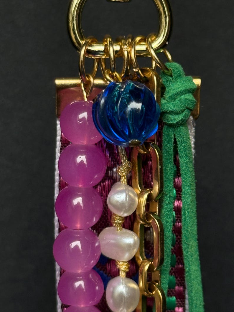Detailed view of upper part with bright blue bead, pink faceted beads, and glossy white pearls on gold chain.