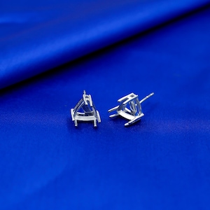 May include: Two silver-colored metal earring settings, each featuring a triangular prong mount designed to hold a gemstone. The settings include a post back for attachment and are displayed as individual components for jewelry assembly.