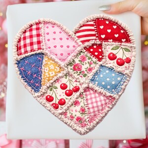 May include: A heart-shaped patchwork item with various fabric patterns, including gingham, polka dots, and floral prints. The design incorporates cherry motifs and is surrounded by a textured border. The item is held against a white background.