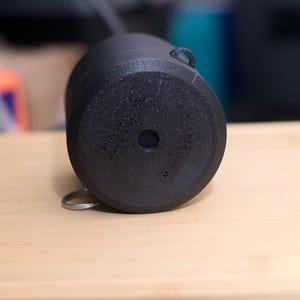 Pode incluir: Uma caneca de cer&acirc;mica preta com uma superf&iacute;cie texturizada, uma pequena al&ccedil;a e um anel de metal preso na parte inferior. A parte inferior da caneca tem o texto "MADE IN USA".