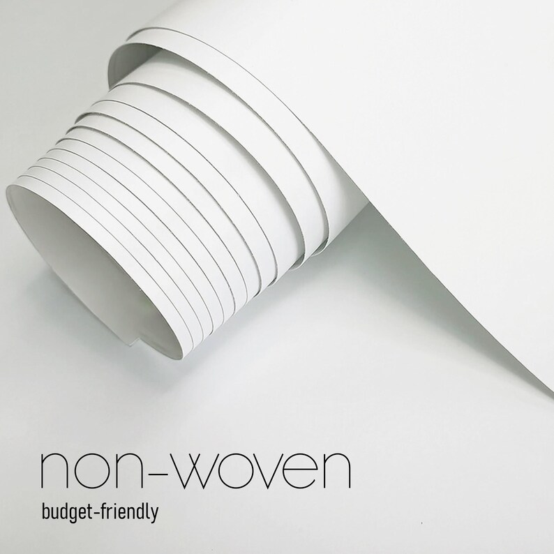 May include: A roll of white non-woven material, partially unrolled, showing layers of the paper. The text "non-woven" and "budget-friendly" are displayed in a minimalist font at the bottom of the image.