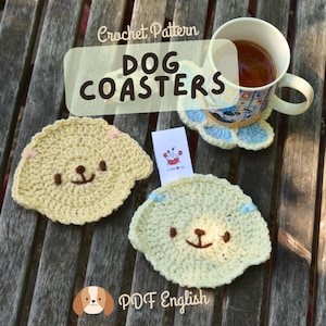 May include: Handmade crochet dog coasters in light yellow with brown and pink accents. The coasters have a dog face design and are shown with a mug of tea. The image includes the text "Crochet Pattern DOG COASTERS" and "PDF English".