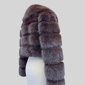 May include: A short, brown fur jacket with a rounded neckline and horizontal fur panels. The jacket is displayed on a white mannequin. The text "AYER ROCKS" is visible in the lower right corner.
