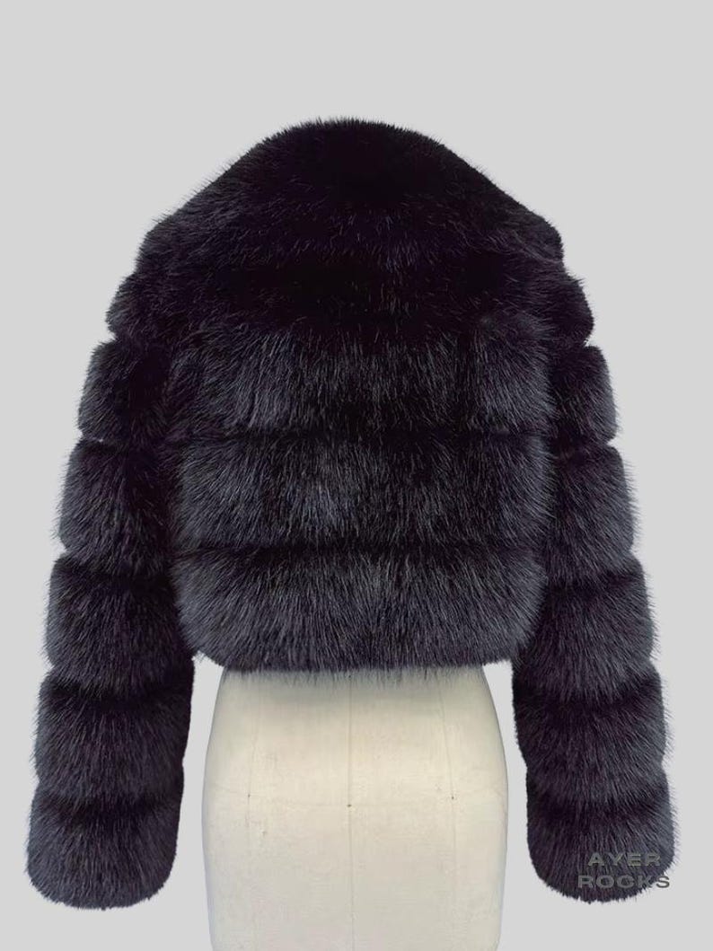 May include: A black fur jacket with a cropped design. The jacket has horizontal bands of fur and long sleeves. The garment is displayed on a mannequin against a light grey background.