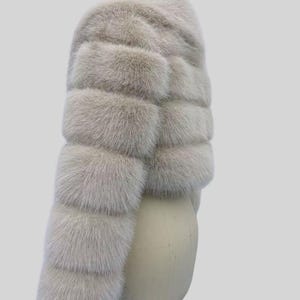 May include: A light grey fur scarf with a layered design. The scarf is made of soft, fluffy fur and is displayed on a mannequin head against a light grey background. The text "AYER ROCKS" is visible in the bottom right corner.