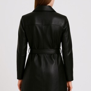 May include: A black, long-sleeved coat with a belted waist. The coat features a notched collar and vertical seams. The model is wearing the coat, viewed from the back, against a plain background.