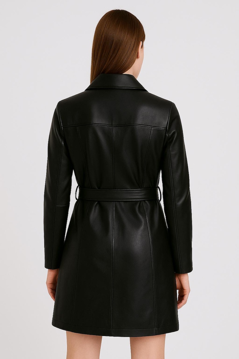 May include: A black, long-sleeved coat with a belted waist. The coat features a notched collar and vertical seams. The model is wearing the coat, viewed from the back, against a plain background.