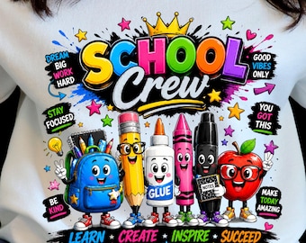 May include: A white sweatshirt featuring a colorful graphic with the text "SCHOOL Crew" and "LEARN CREATE INSPIRE SUCCEED". The design includes cartoon characters of a blue backpack, a yellow pencil, a glue bottle, a pink crayon, a black marker, and a red apple.
