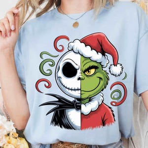May include: Light blue t-shirt featuring a split design of Jack Skellington and the Grinch in Santa hats. The design includes green and red swirls, a black bow tie, and a red Santa suit.