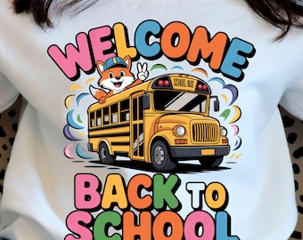 May include: White sweatshirt with a colorful graphic that says "WELCOME BACK TO SCHOOL". The graphic features a yellow school bus with a fox character waving from the window. The text is in bubble letters.
