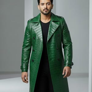 Könnte beinhalten: Ein grüner Trenchcoat mit Krokodilleder-Textur. Der Mantel hat ein doppelreihiges Design mit schwarzen Knöpfen, einem Reverskragen und einem Gürteldetail an den Ärmeln. Der Mantel ist knielang.