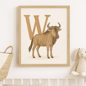 Könnte beinhalten: Gerahmter Druck mit einer braunen Gnu-Illustration. Ein großer brauner Buchstabe "W" befindet sich hinter dem Tier. Das Kunstwerk ist in einem hellen Holzrahmen, passend für ein Kinderzimmer.