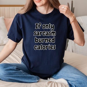 Humorous typography design on a short-sleeve t-shirt, reading "If only sarcasm burned calories" in a bold, fun font. An essential piece for anyone looking for an if only sarcasm burned calories tee, a gift for gym rats and sarcastic friends, or relatable workout gear.